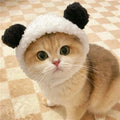 Cute kitten wearing a plush white and black Panda Pod panda bear costume hat
