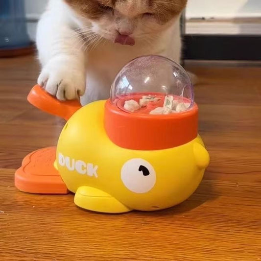 Cat pressing the lever of the yellow Duck Duck Goose press and spin treat dispenser toy