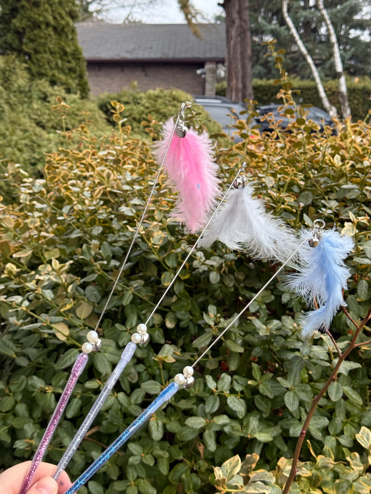 Assorted fairy wand cat teaser toys with loose feathers and bells in pink, grey, and blue 